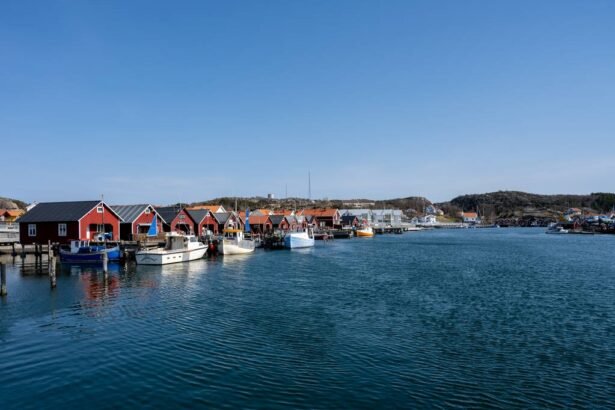 A tranquil harbor scene featuring boats and quaint red-roofed buildings along a calm waterway under a clear blue sky.